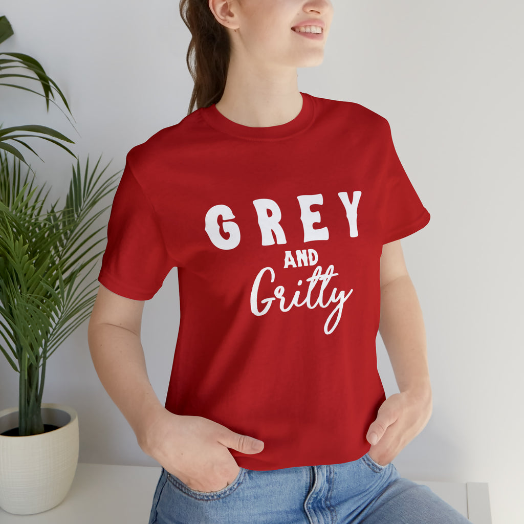 Red short sleeve with white lettering reading "Grey and Gritty". Model wears this with jeans and her hands tucked into the pockets.