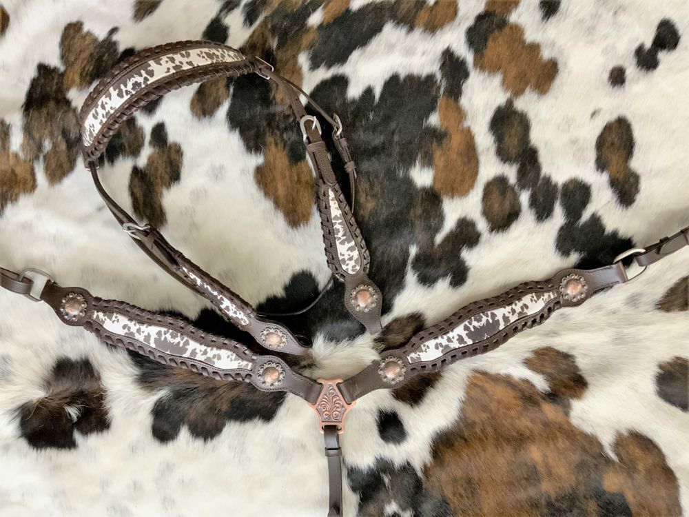 ark oil western headstall set with cowhide inlay. Copper conchos are at the end of the leather work. Leather whip stitch wrap the edges of the headstall set.