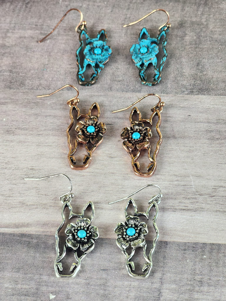 Three horse head floral earrings. One has a turquoise finish with a turquoise colored stone. One has a copper finish with a turquoise colored stone. And one has the antique silver with a turquoise colored stone.