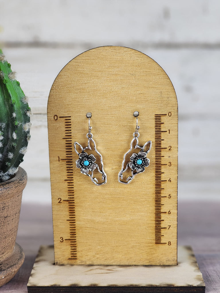 Silver horse head floral earring hang from the wooden measuring reading about 1.5".