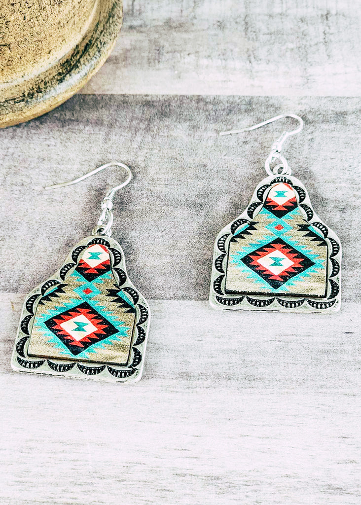 Southwestern cow tag leather earring with stamped designs. Teal, red, and white tribal design. 
