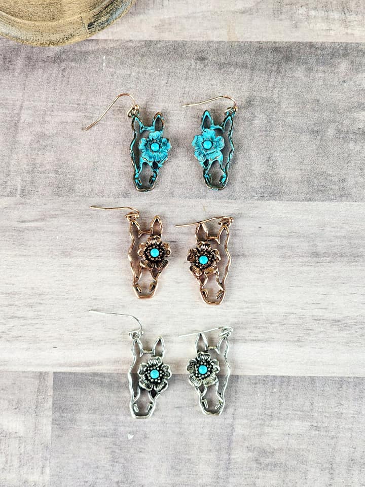 Three horse head floral earrings. One has a turquoise finish with a turquoise colored stone. One has a copper finish with a turquoise colored stone. And one has the antique silver with a turquoise colored stone. 