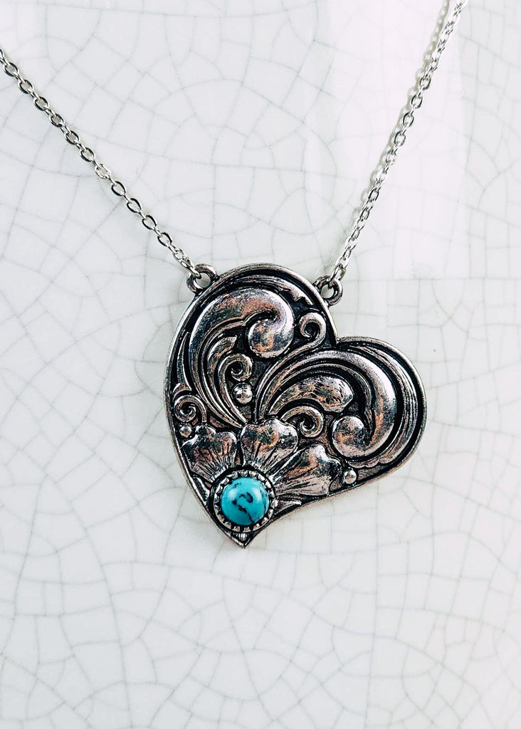 Western cowgirl heart antique silver floral design and a turquoise-like stone acting as the middle of flower. Chain necklace with clasp. 