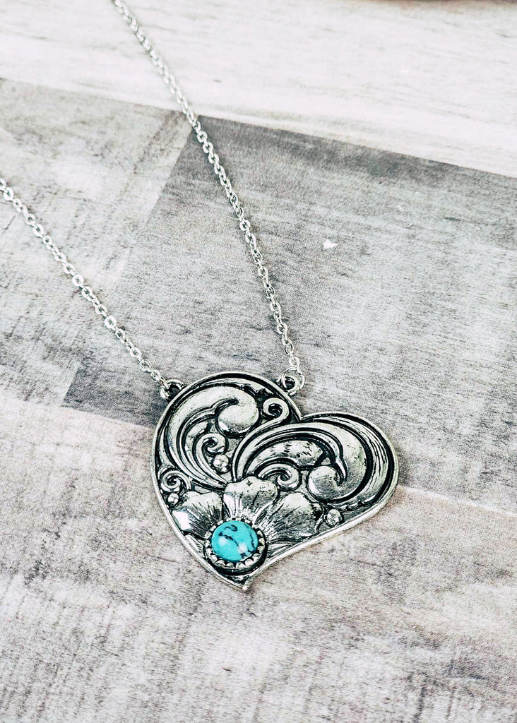 Western cowgirl heart antique silver floral design and a turquoise-like stone acting as the middle of flower. Chain necklace with clasp. 