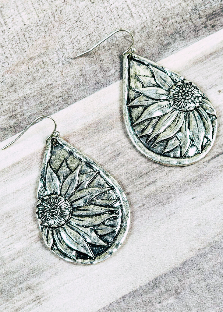 Western sunflower antique silver earrings on wooden table top. 