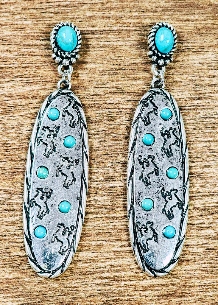 Wild cowgirl earrings with stamped bronc rider in the silver. Turquoise stones are set around the broncs and in the stud area. 