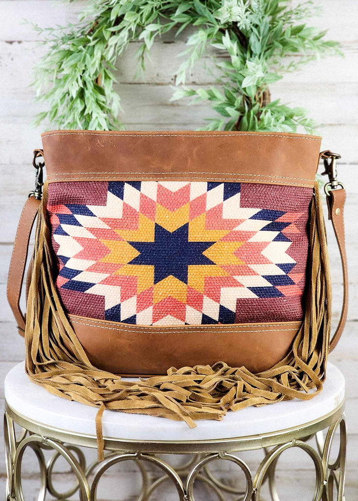 Straight on view of the Sedona Star and leather panels. Fringe wrapped to center of purse. Shoulder straps hand at the side of the purse. 