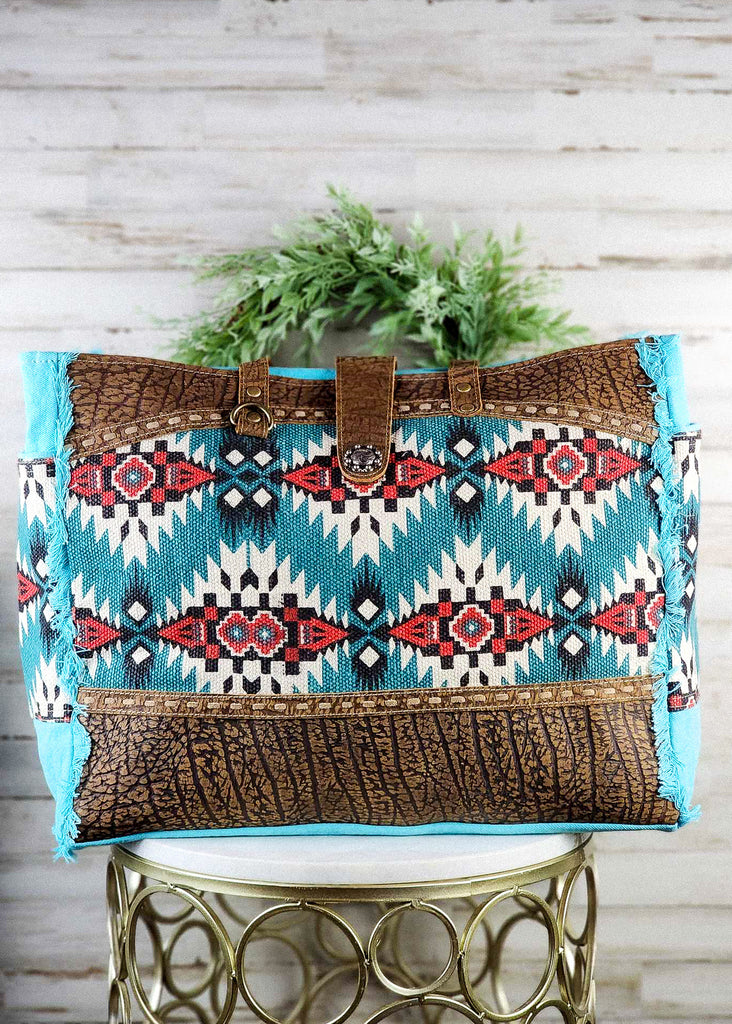 Front view. Cowgirl Tote bag with beautiful hues of turquoise, ivory, and red.  Chocolate leather panels. 