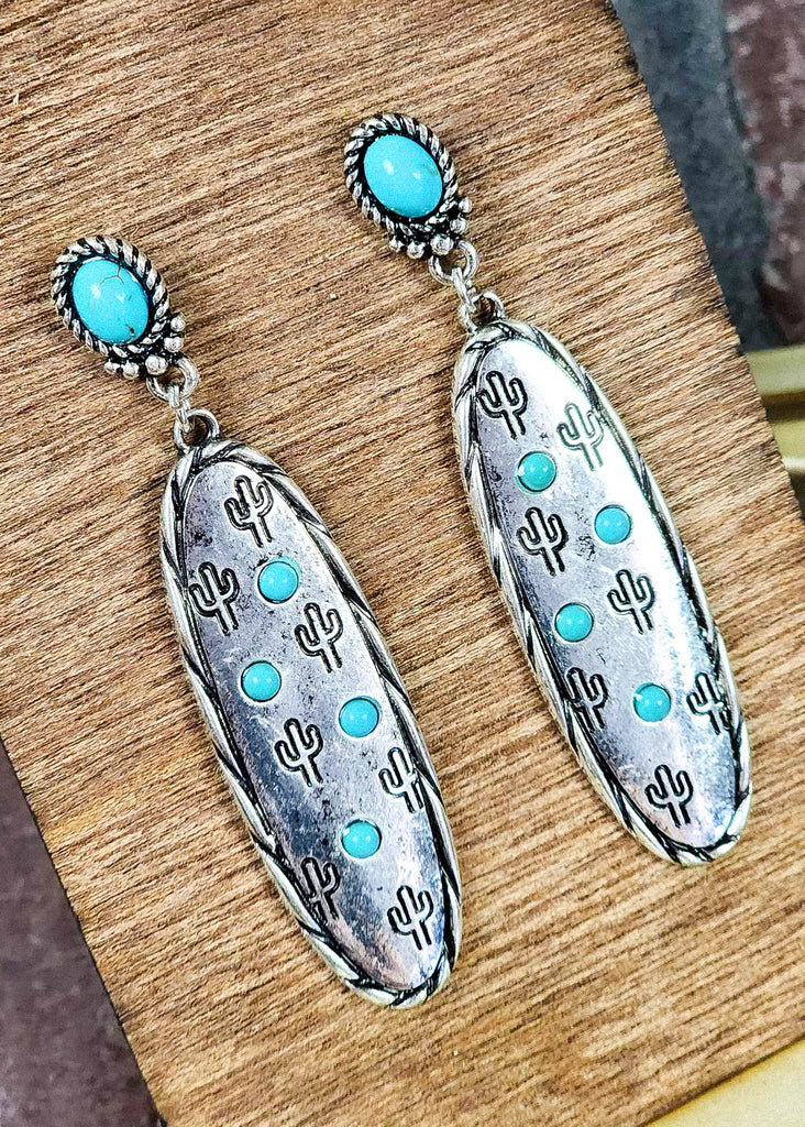 Southwestern cowgirl earrings with turquoise like stones for the stud and on the antique silver with stamped cactus and twisted design on wood background.