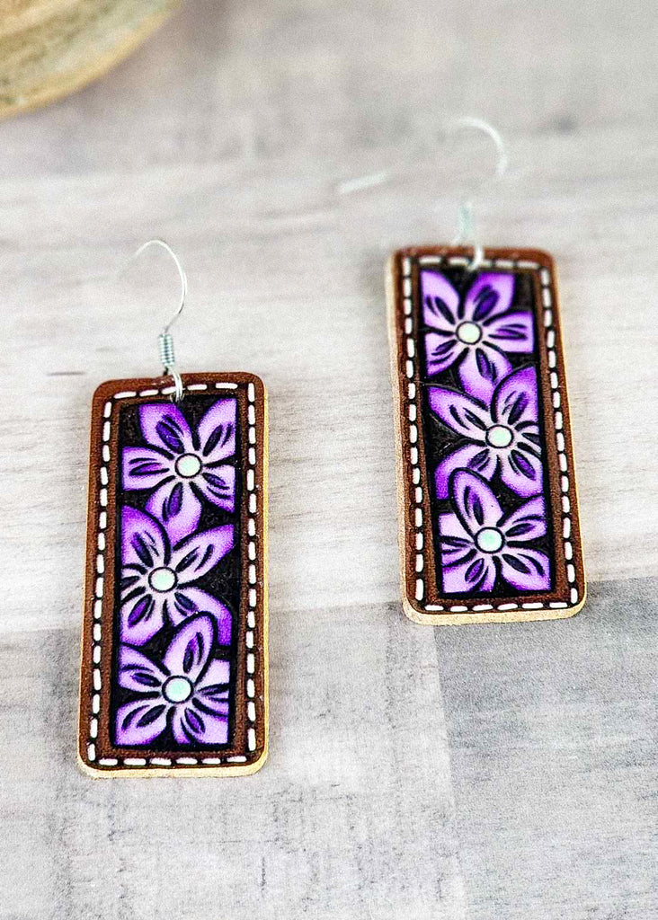 Purple cowgirl painted earrings with floral tooling and white stitching. 