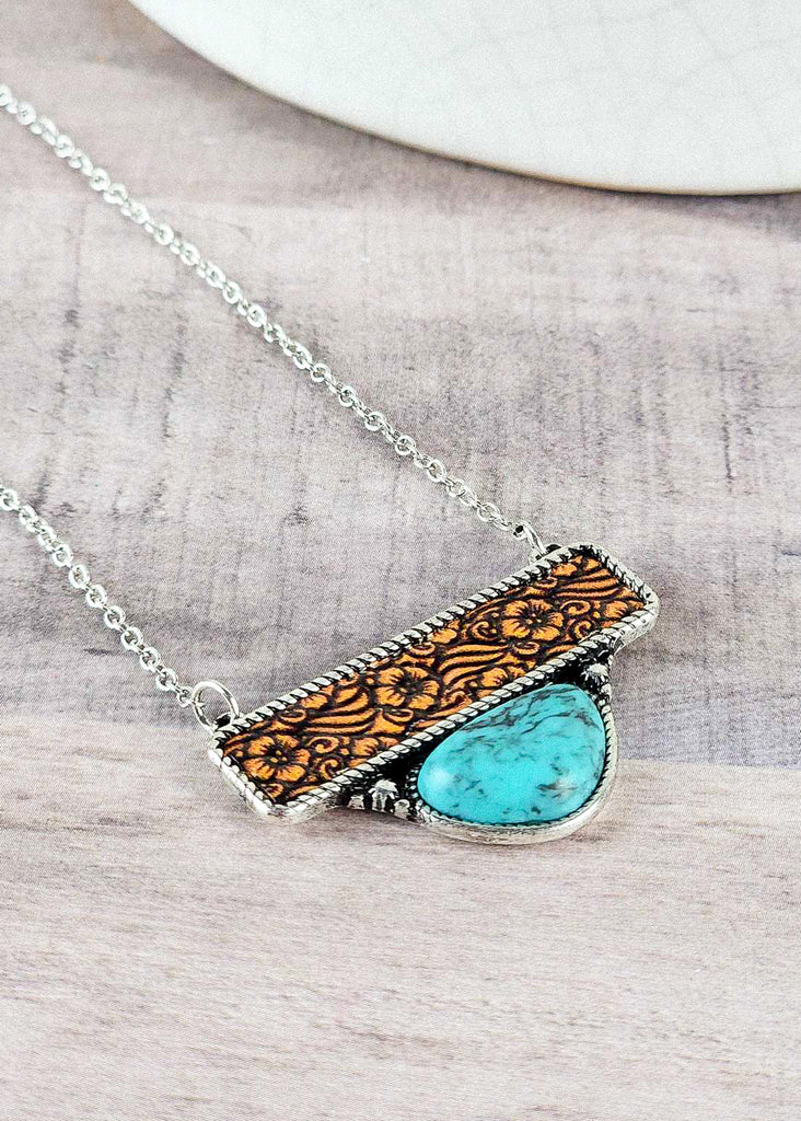 Cowgirl western necklace with leather floral tooling and a turquoise like stone encased in antique silver design. 