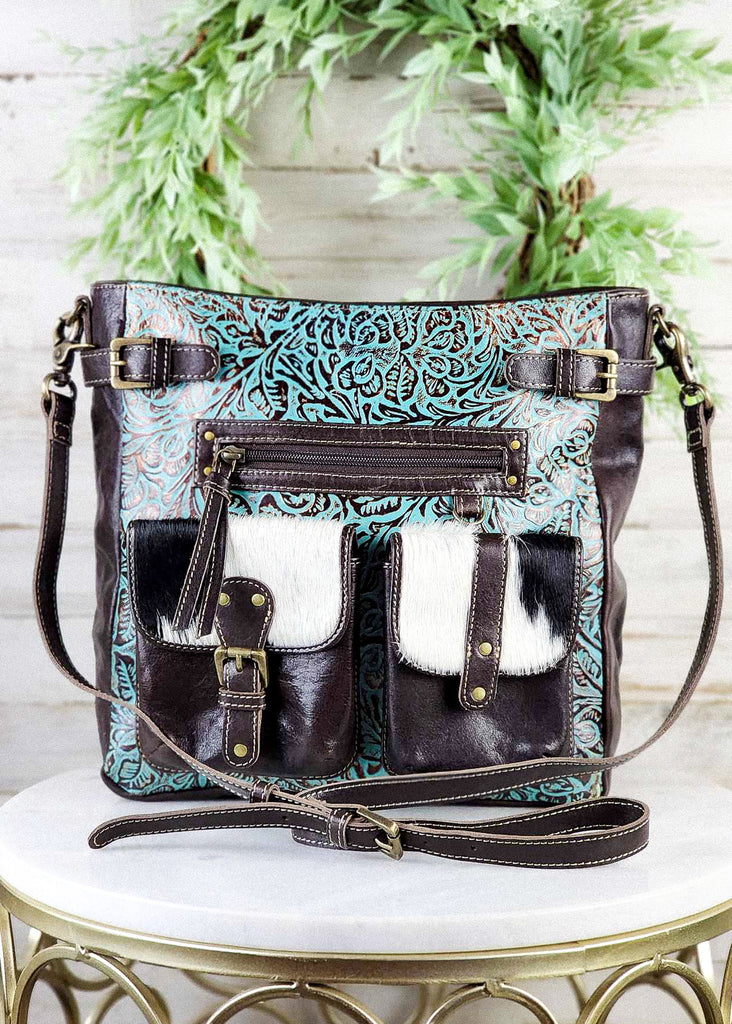 Cowgirl purse with turquoise hand tooled leather, hair on hide front pockets, and adjustable straps. 