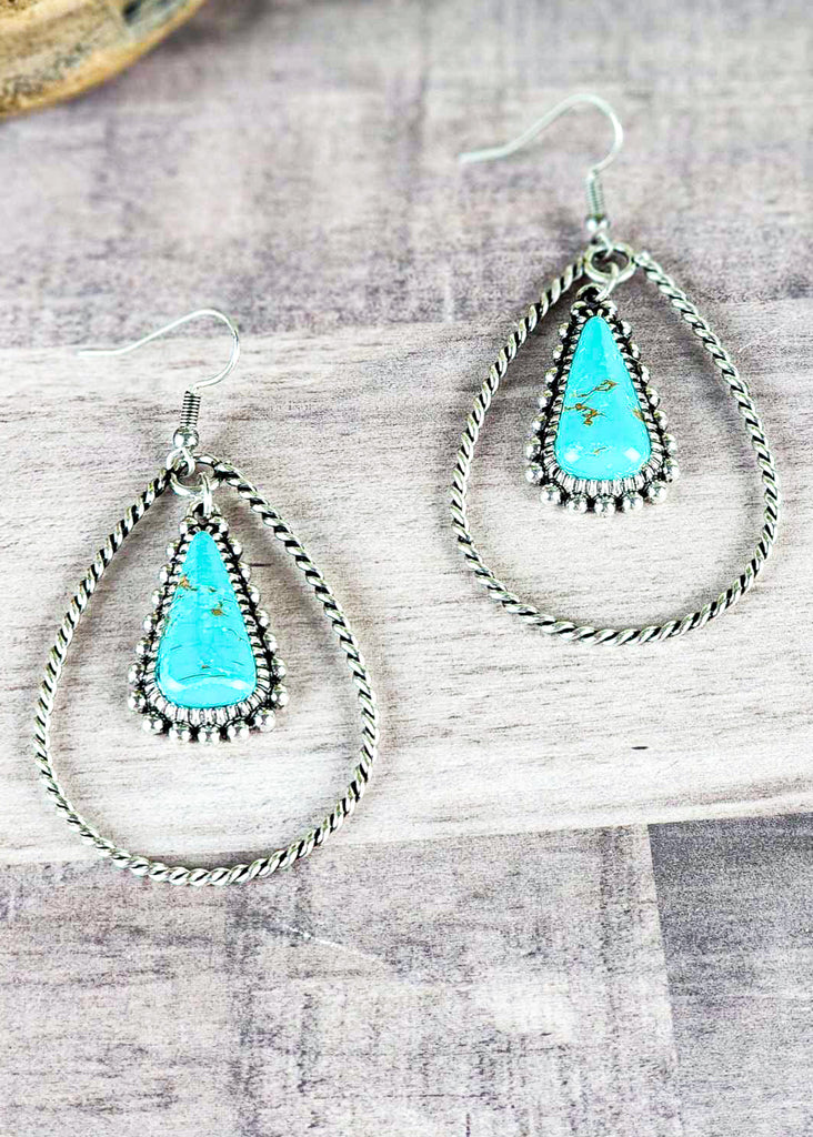 Cowgirl twisted antique silver hoops encompassing turquoise-like stone set in antique silver.