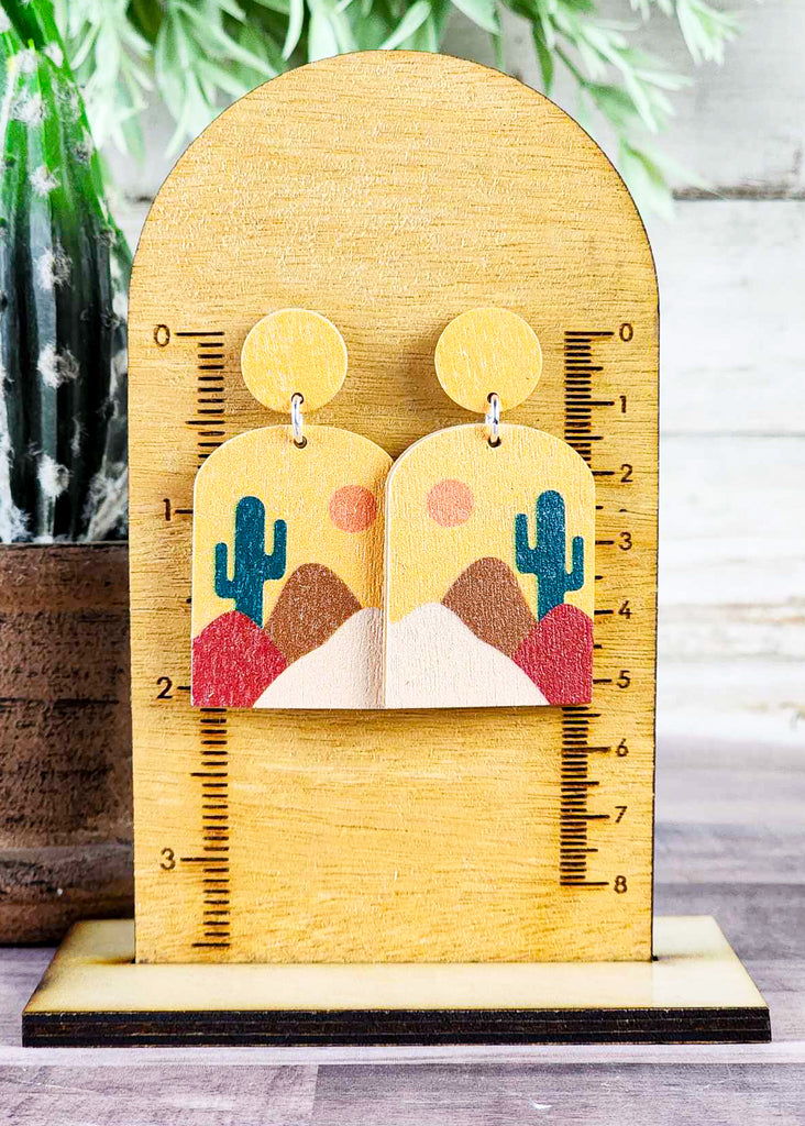 Southwestern earring with a desert scenery. Yellow wood studs that connect to the desert scenery by a small metal hoop. Earrings hang about 2 inches. 