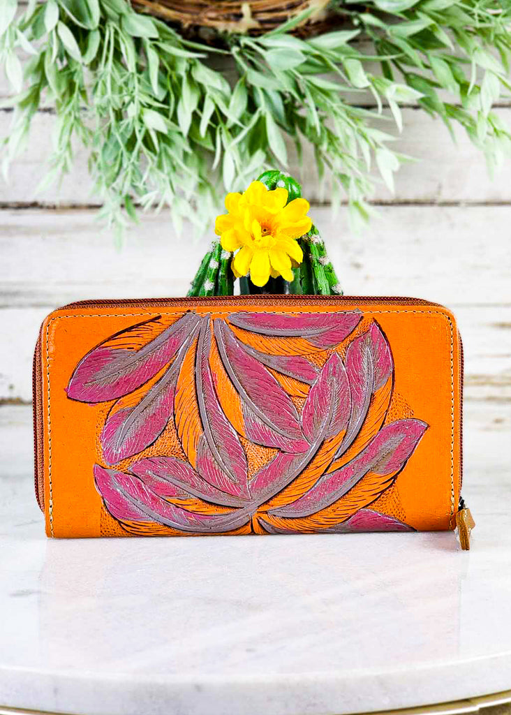 Front view. Bright orange leather wallet with pink feather tooling. 