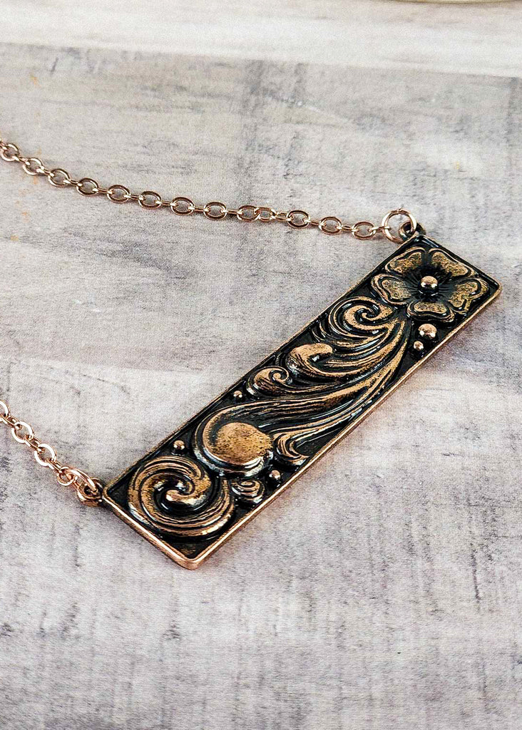 Cowgirl floral tooling copper bar necklace with chain hold. 