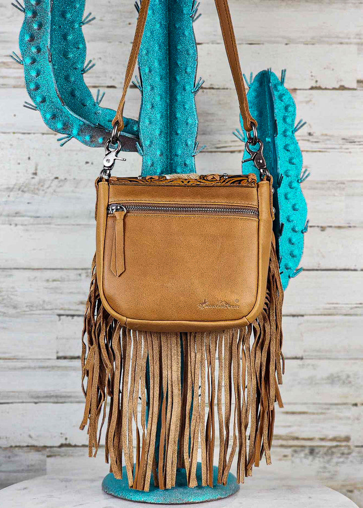 Genuine brown leather shown on backside of bag with matching fringe dangling down. Back zippered pocket is visible. 