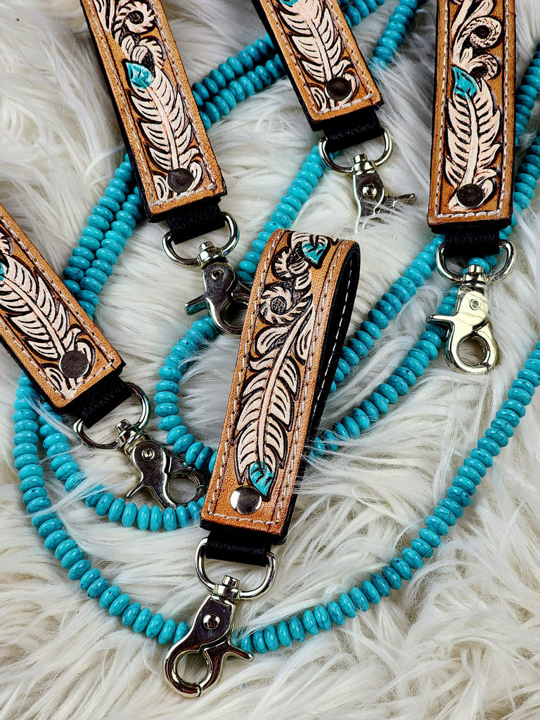 tooled leather feather western keyrings on white rug with turquoise beads