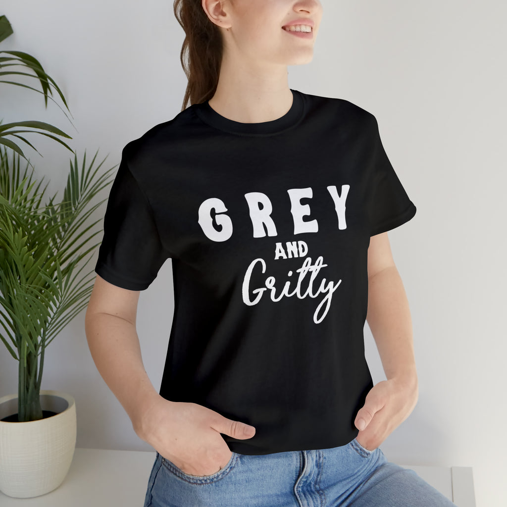 Black short sleeve with white lettering reading "Grey and Gritty". Model wears this with jeans and her hands tucked into the pockets.