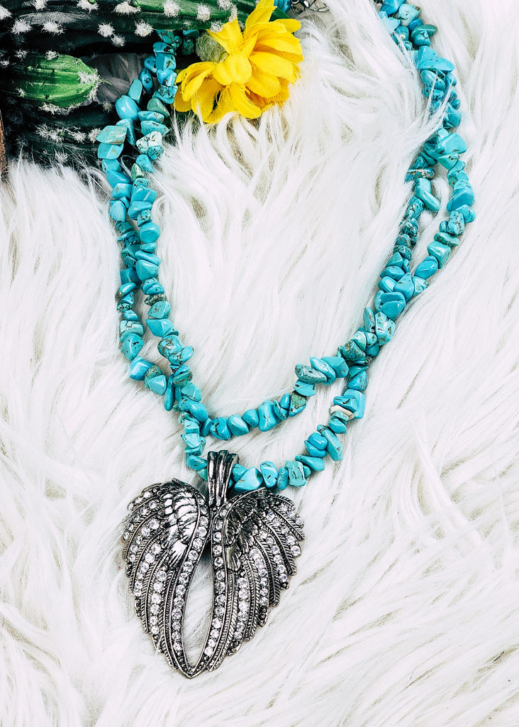 Cowgirl necklace with angel wing heart pendant with diamond-like stones and two strands of turquoise-like stones. 