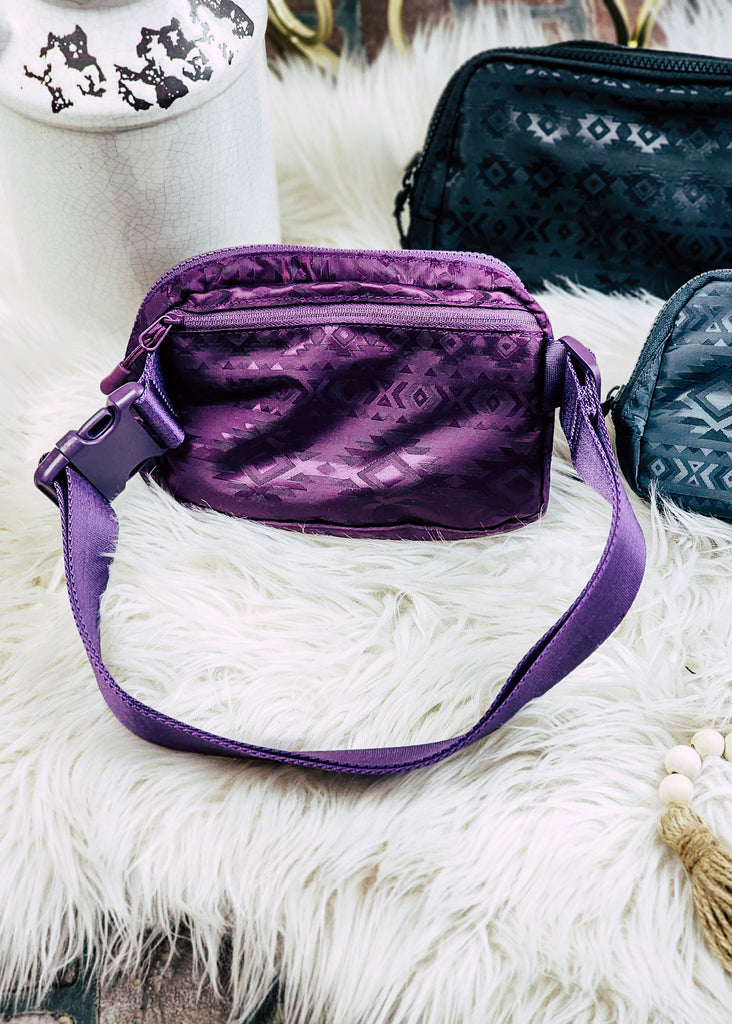 Purple Aztec embossed fanny pack. Back zippered pocket visible along with adjustable waist strap with clip. 