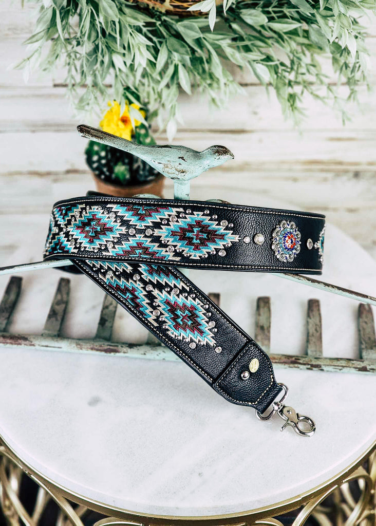 Western black & turquoise aztec guitar or purse strap with diamond like jewels throughout the strap. Silver concho with blue, purple, and red jewels. 