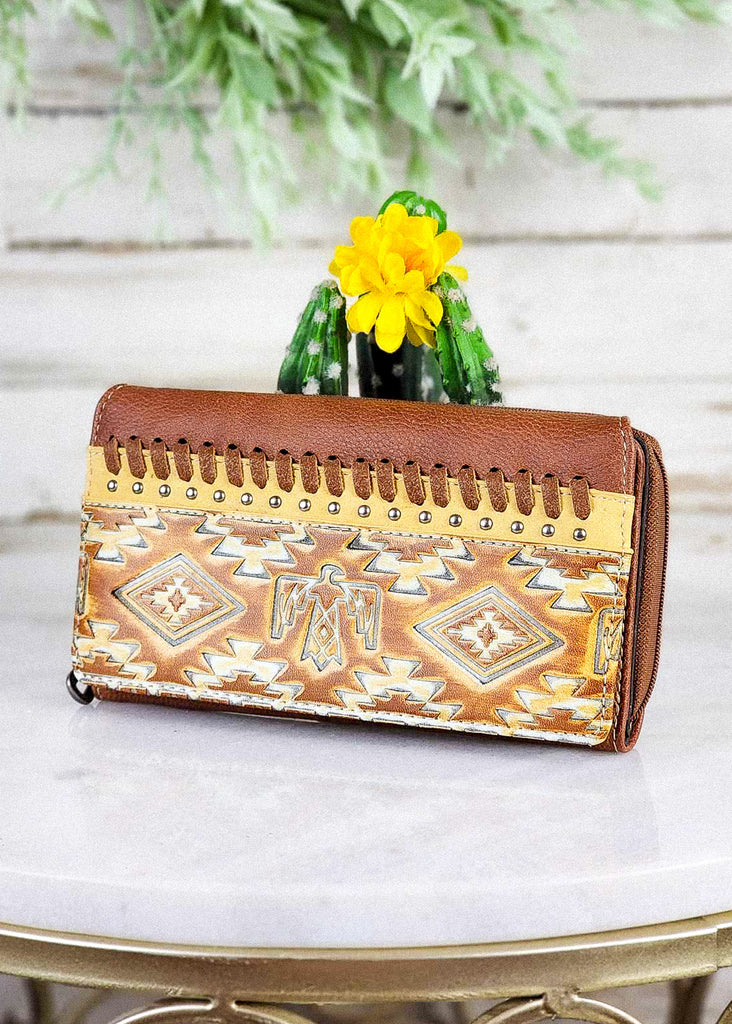 Brown Aztec Thunderbird Embossed Wallet on white table with green cactus decor, western fashion wallet