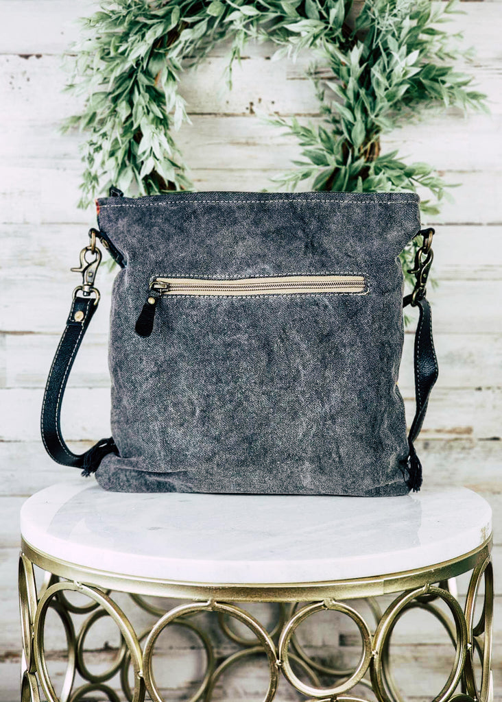Black canvas handbag with side zipped pocket. Backside of purse is shown. 