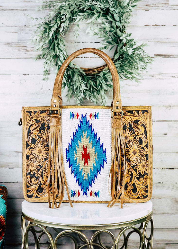 concealed carry western handbag with aztec pattern and tooled floral and fringe, shown on white table with green decor