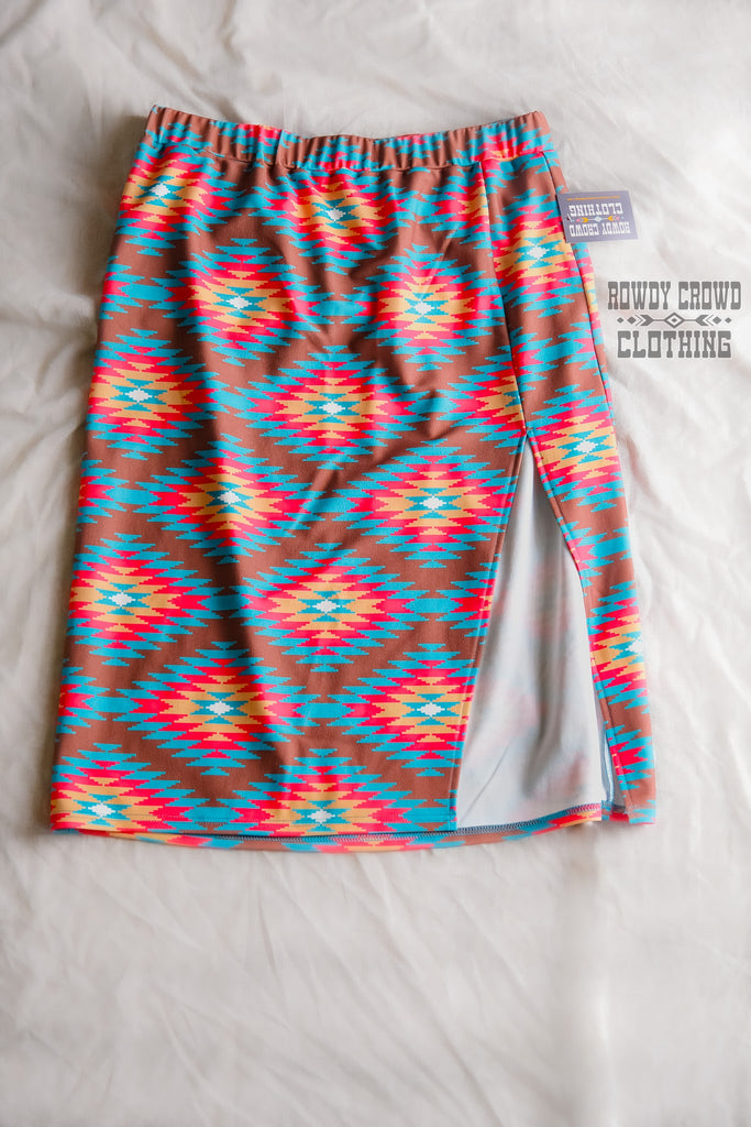 Southwestern tribal printed knee-length skirt with slit up the side to mid-thigh. Brown is the main color with tribal design in bright teal, pink, and yellow.