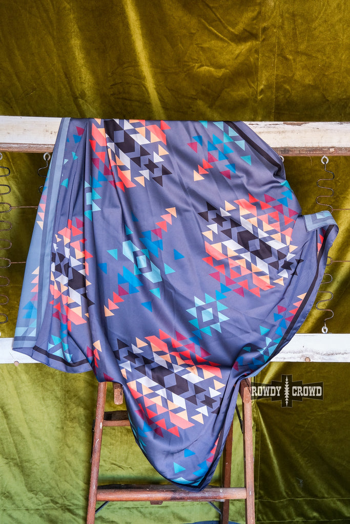 Grey wildrag with southwestern tribal rainbow pattern. Hangs from bed spring against a green background. 
