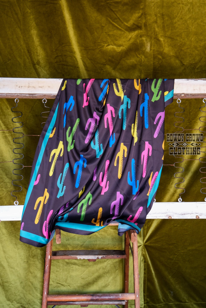Black wildrag with multi colored cacti prints with teal strip on the borders. Hangs off old bed spring. 