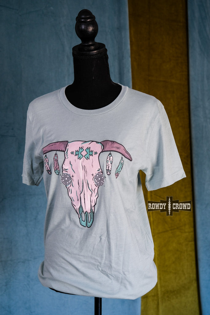 Teal short sleeve tee with a cow skull with disco eyes and feathers hanging from the steer horns. Shirt hangs from mannequin. 