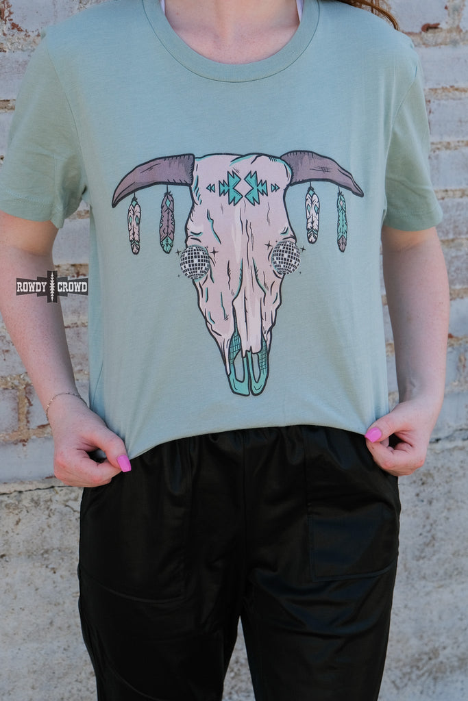 Teal short sleeve tee with a cow skull with disco eyes and feathers hanging from the steer horns.