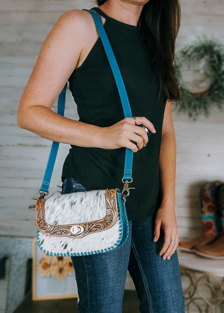 Daydreams Cowhide Crossbody Handbag on model with western decor and cowboy boots in background