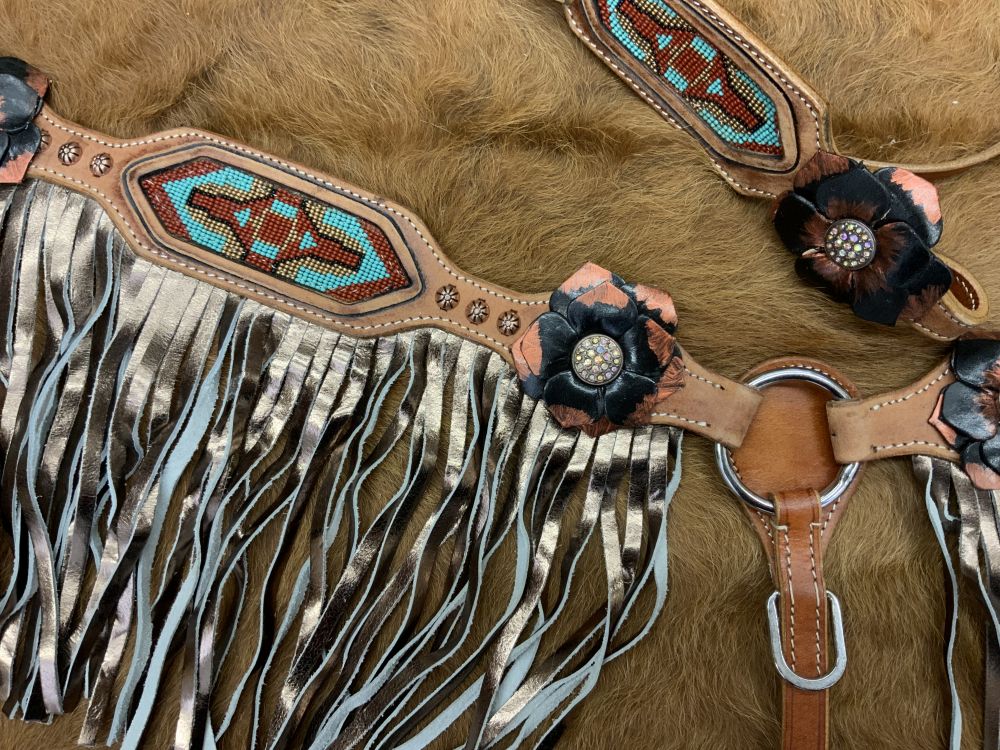 Western light oil headstall set with beaded aztec inlays and gold fringe. Floral conchos decorate the piece with small copper colored small studs. Copper and black floral conchos with a jeweled center are visible. 