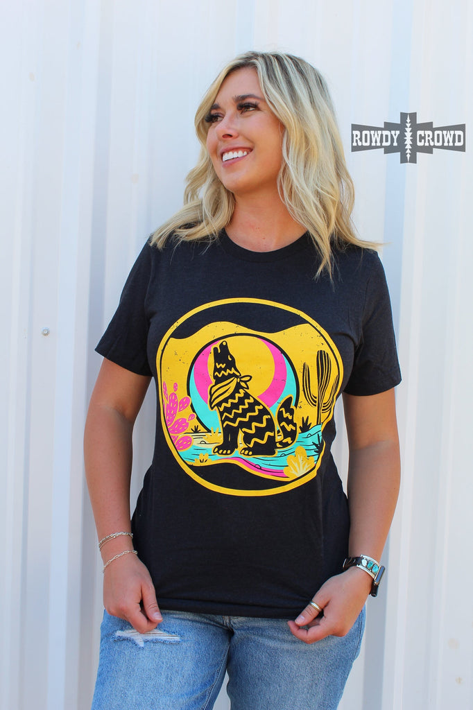 Heather black short sleeve tee with a yellow, blue, and pink desert scene of a coyote howling at the moon. 