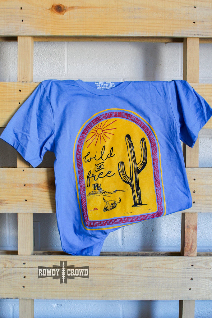 blue western graphic tee with western wild and free design, hanging on wood pallet