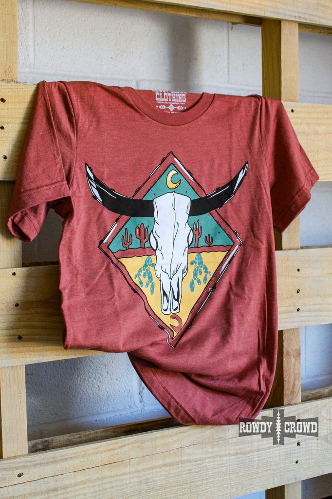 rust colored western graphic tee with steer skull and cactus design, hanging on wood pallet