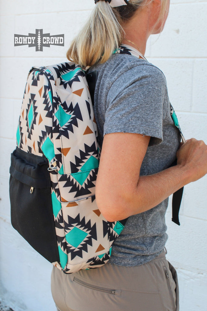 Western backpack with tan canvas and a tribal design with teals and oranges. Black canvas pocket with zipper pocket. Matching canvas for side pockets. 