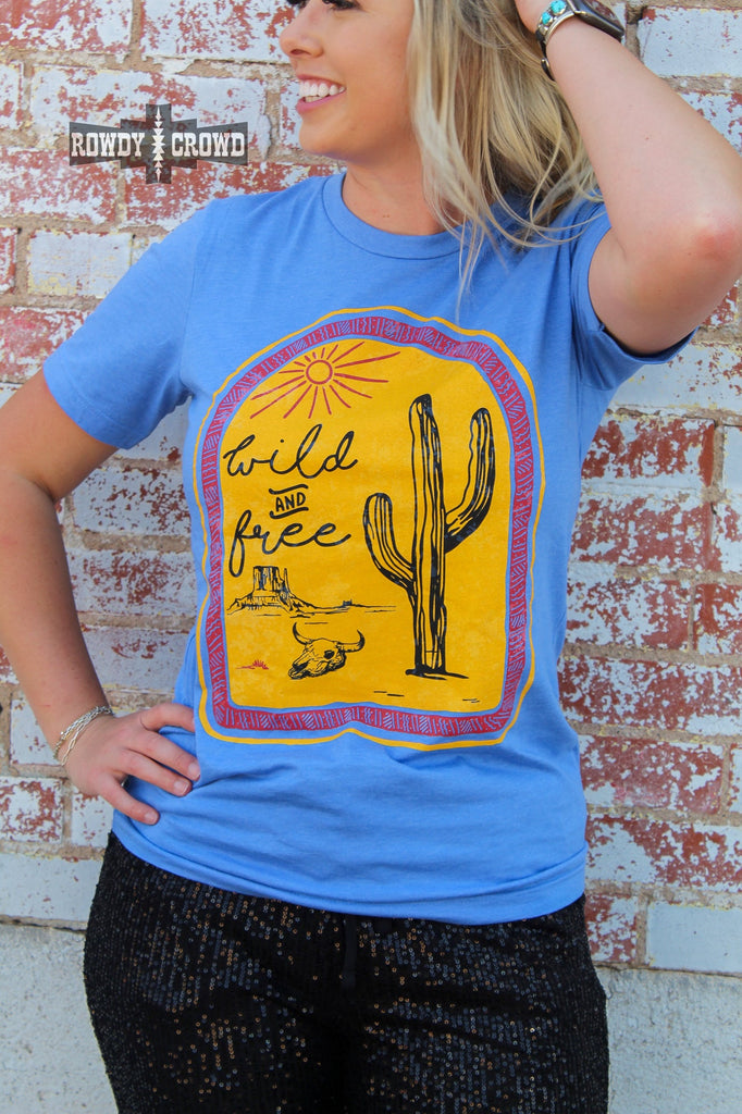 blue western tee with wild and free cactus cactus design, model is blonde with black sequin pants, brick background