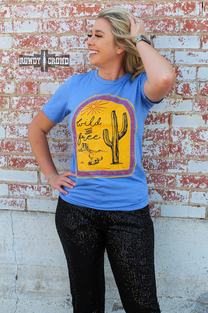 blue western tee with wild and free cactus cactus design, model is blonde with black sequin pants, brick background