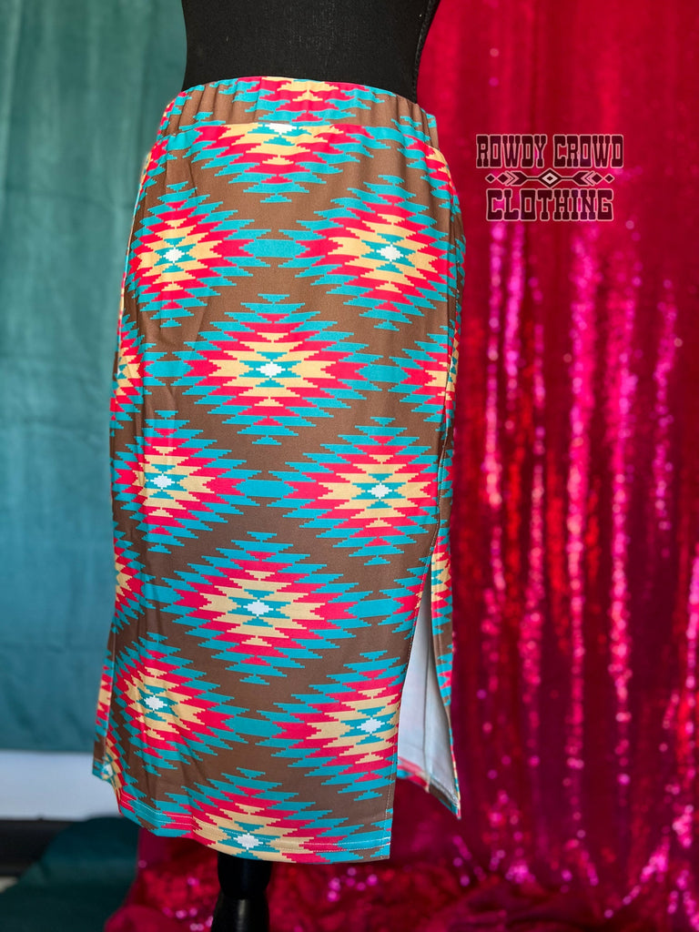 Southwestern tribal printed knee-length skirt with slit up the side to mid-thigh. Brown is the main color with tribal design in bright teal, pink, and yellow.