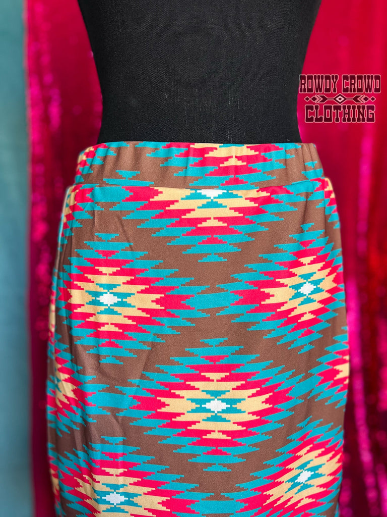 Southwestern tribal printed knee-length skirt with slit up the side to mid-thigh. Brown is the main color with tribal design in bright teal, pink, and yellow.