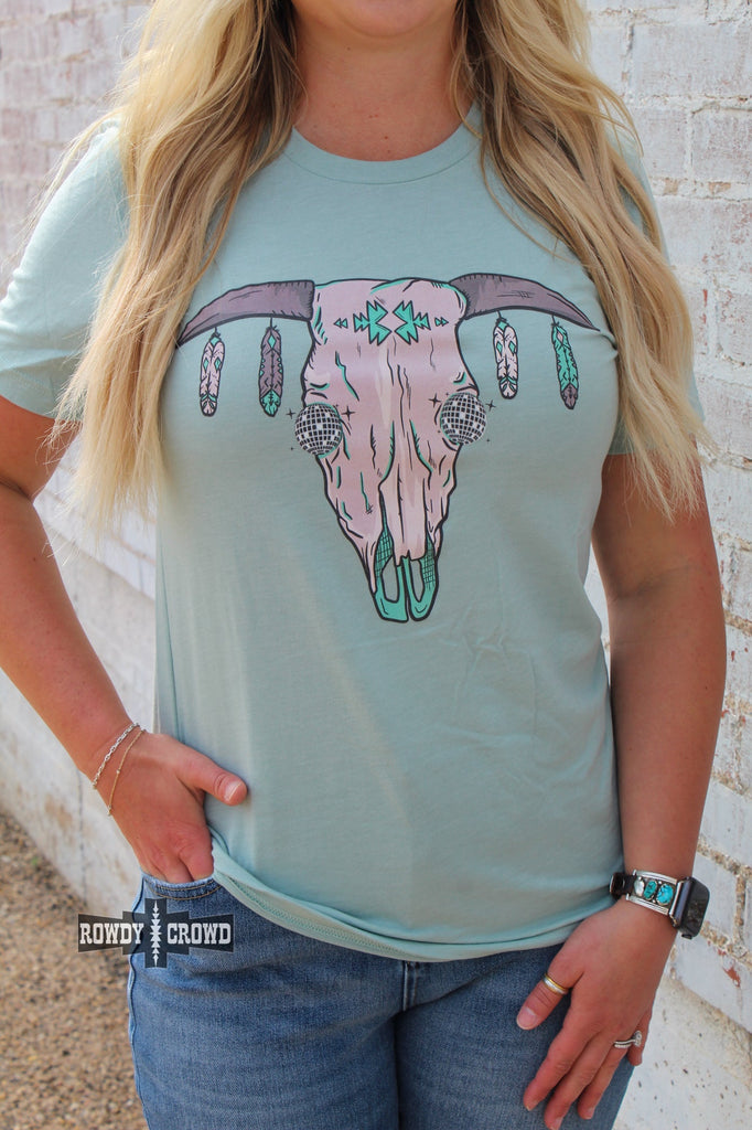 Teal short sleeve tee with a cow skull with disco eyes and feathers hanging from the steer horns.