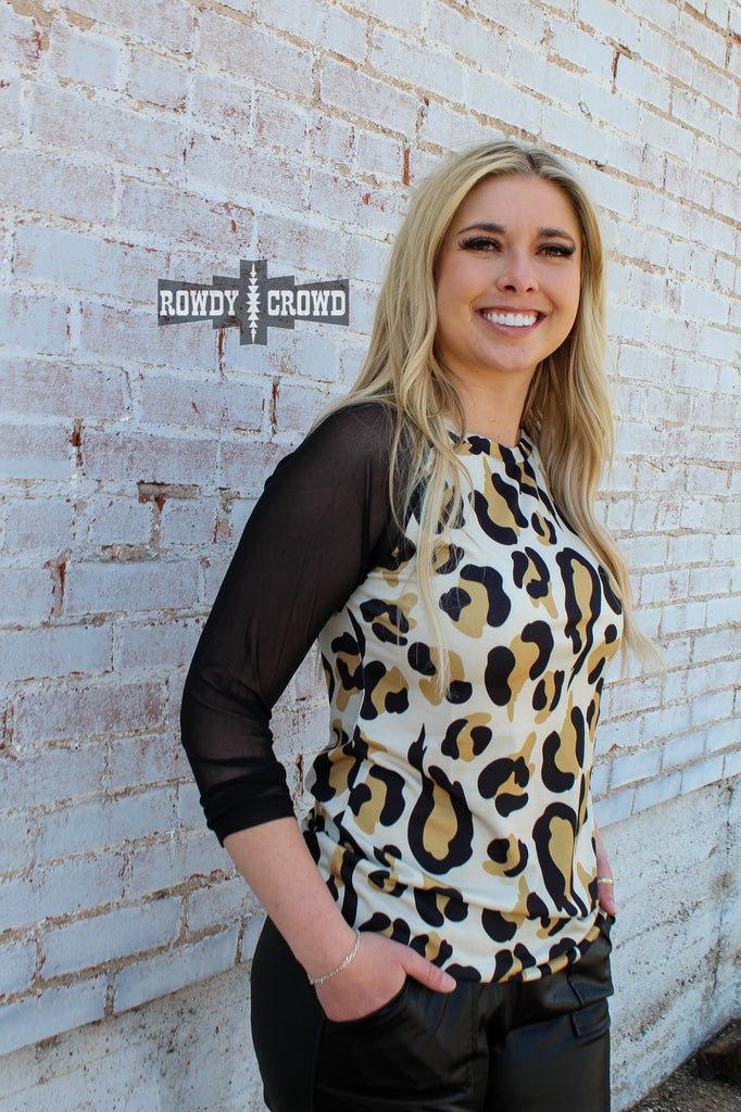 Cheetah long sleeve shirt with black mesh sleeves. Model wears this with leather joggers against a white brick wall. 