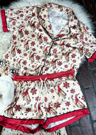 red and cream santa bronc silky pajamas, two piece outfit laid on a white fluffy rug with white slippers 