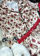 red and cream santa bronc silky pajamas, two piece outfit laid on a white fluffy rug with white slippers 