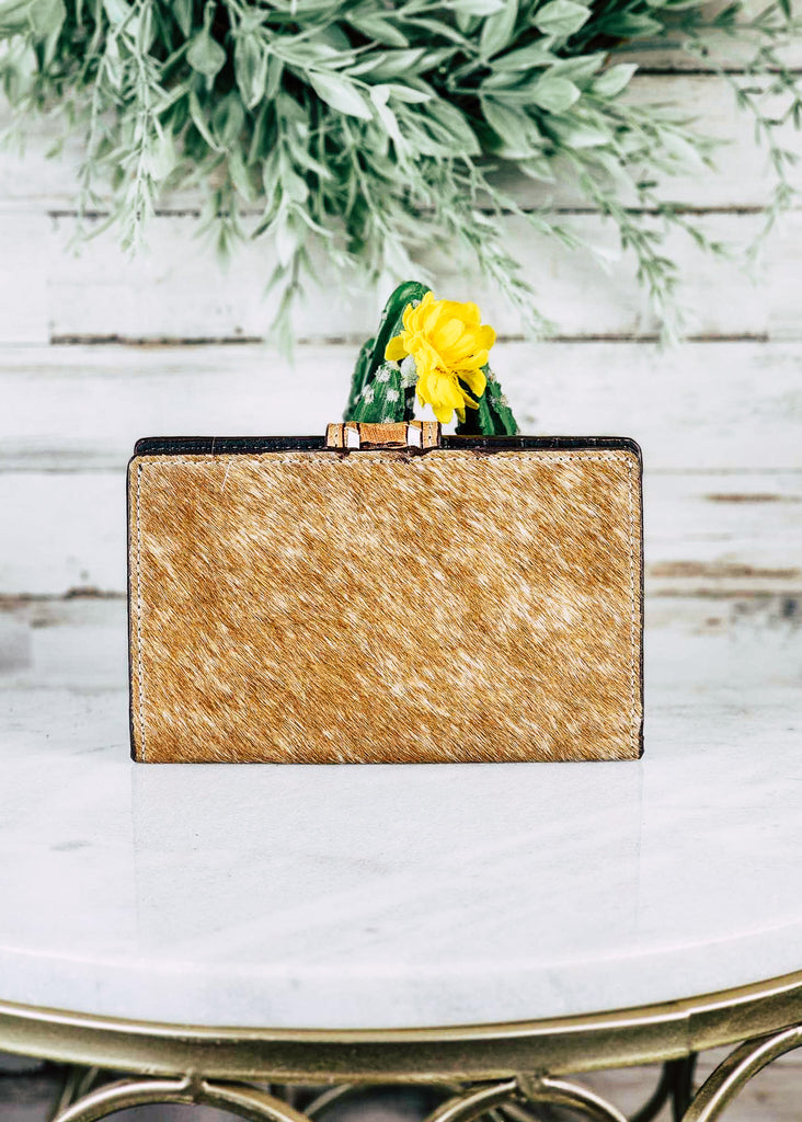 Southwestern Cowhide Buckstitch Wallet pictured on white table with cactus and green decor in the background