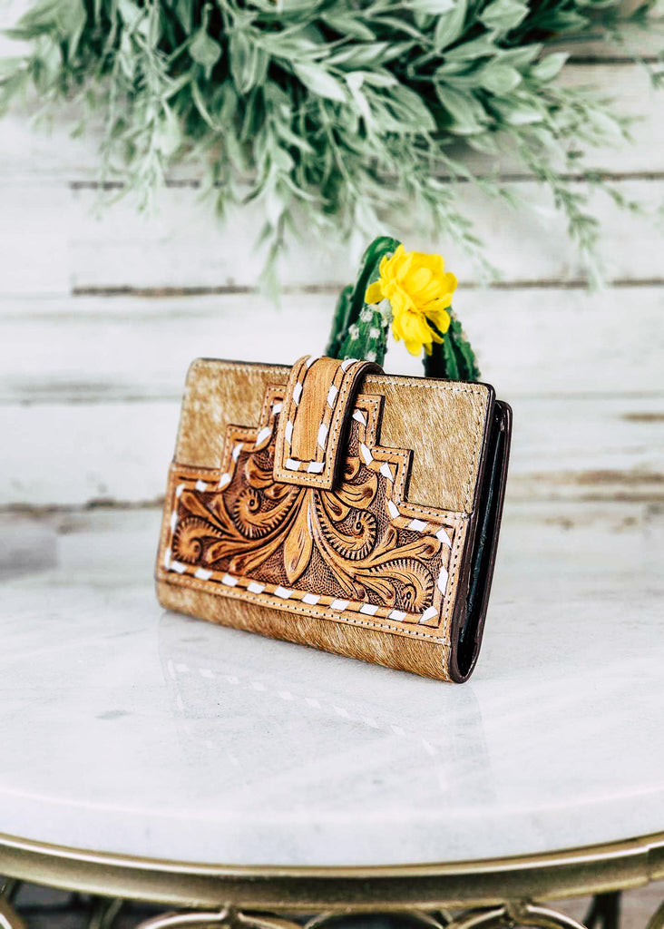 Southwestern Cowhide Buckstitch Wallet pictured on white table with cactus and green decor in the background